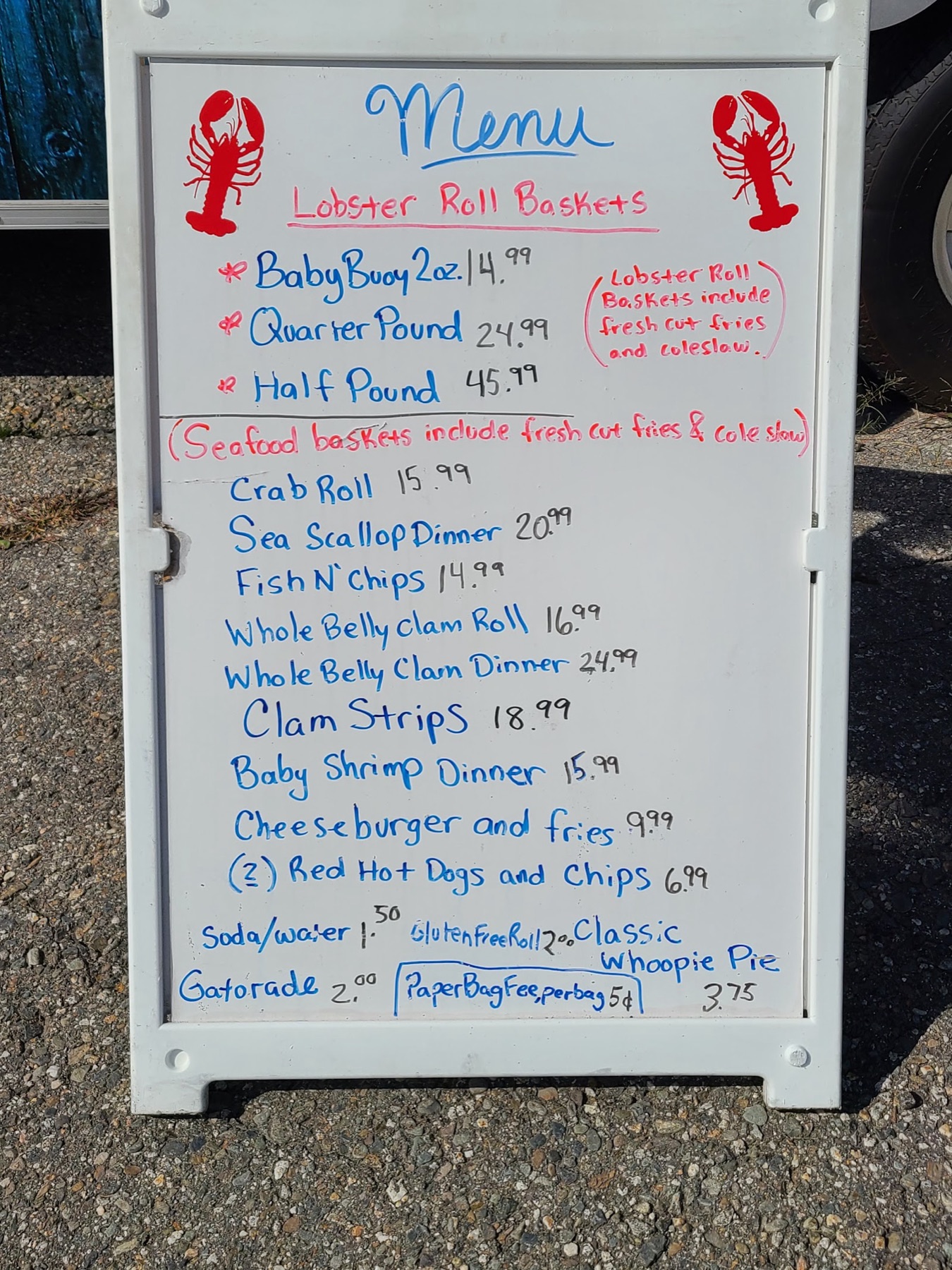 The truck's hand-lettered menu board listing lobster roll baskets, seafood baskets and prices.